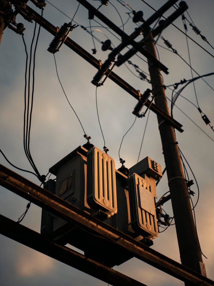 hero-about A dramatic shot of a transmission tower with power lines silhouetted against a sunset sky.