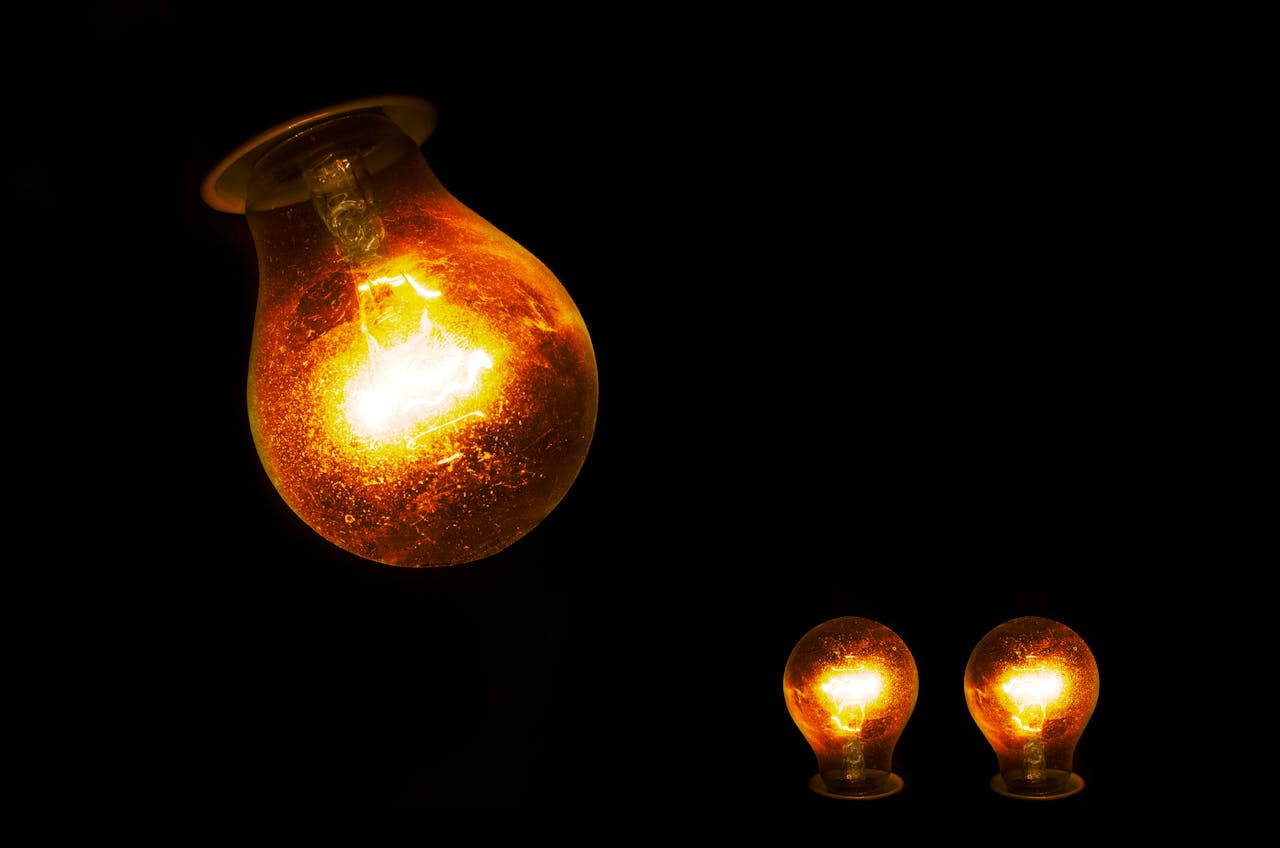services-01 Close-up of illuminated incandescent light bulbs, showcasing warm glowing light against a dark backdrop.