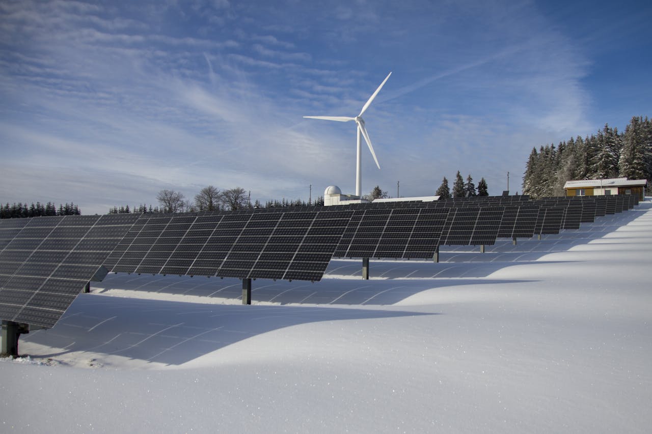 hero-homepage Solar panels and wind turbine in a snowy landscape, showcasing renewable energy sources.